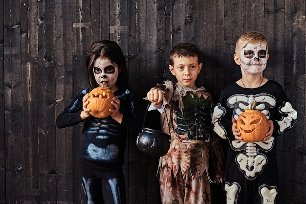 Tre bambini carini in costumi spaventosi durante la festa di Halloween in una vecchia casa. Concetto di Halloween.