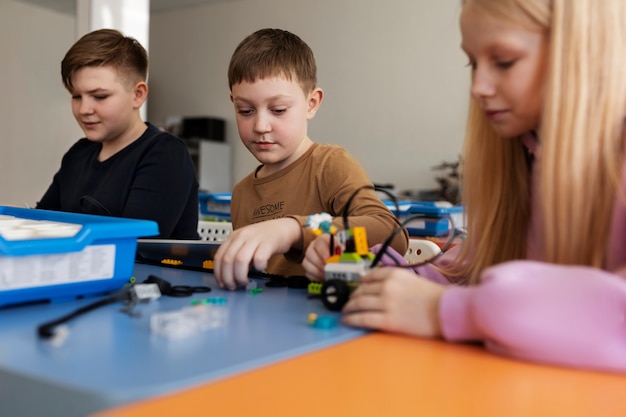 Tre bambini che costruiscono un robot usando parti elettroniche