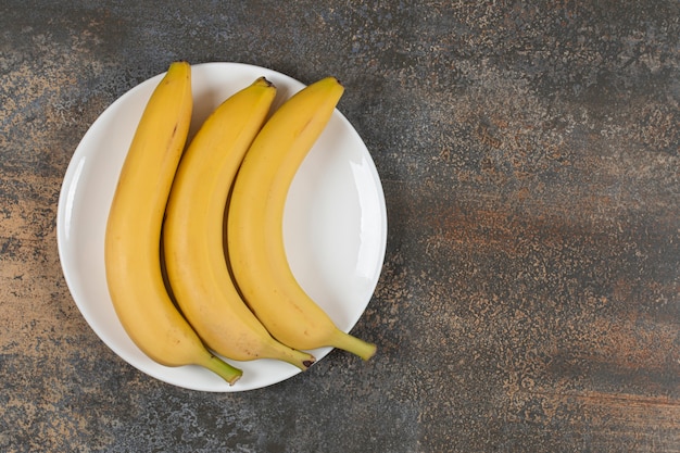 Tre banane mature sulla zolla bianca.