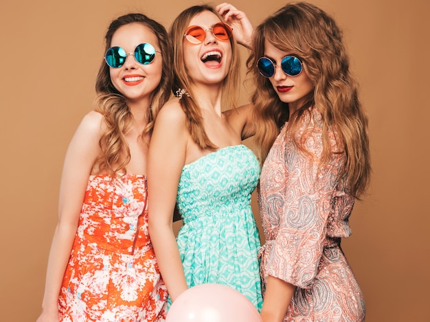 Tre belle donne sorridenti in abiti estivi. Ragazze in posa Modelli con palloncini colorati. Divertirsi, pronti per la festa di compleanno o festa