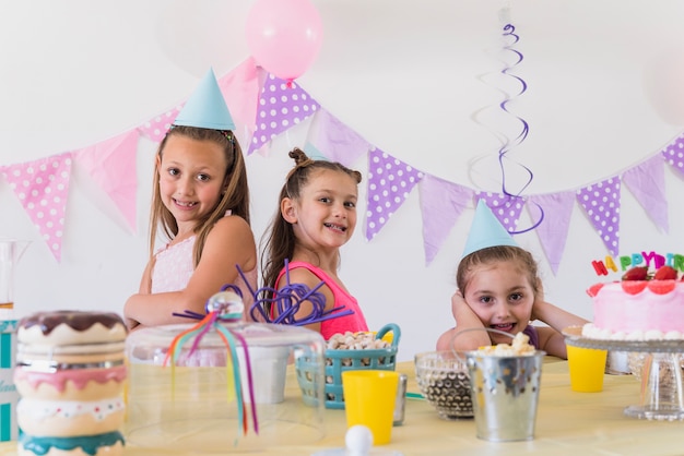 Tre belle ragazze sorridenti che presentano alla festa di compleanno