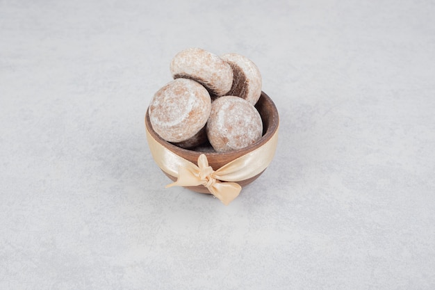 Tre biscotti dolci con fiocco dorato sulla ciotola di legno