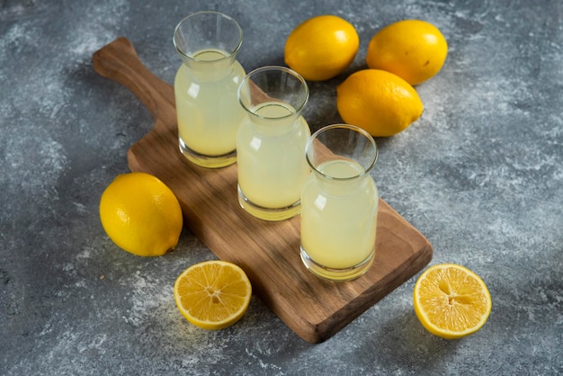 Tre brocche di vetro di limonata fredda su tavola di legno