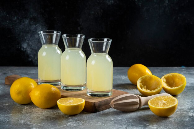 Tre brocche di vetro di succo di limone su tavola di legno.