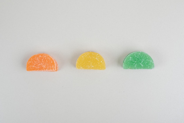 Tre caramelle di gelatina colorate sulla superficie bianca