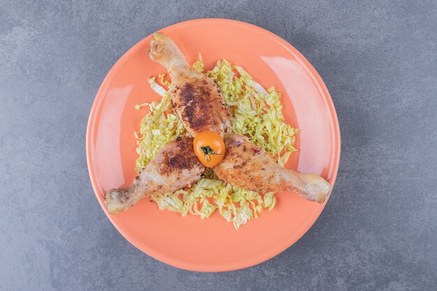 Tre cosce di pollo sul piatto arancione.