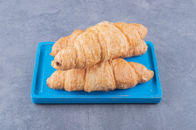 Tre croissant fatti in casa freschi sul bordo di legno blu.