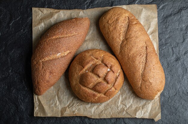 Tre diverse pagnotte di pane su sfondo nero.