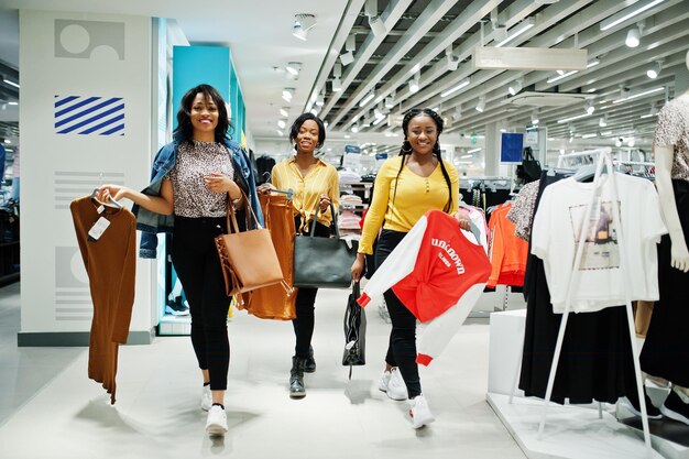 Tre donne africane che scelgono i vestiti al negozio Giorno dello shopping