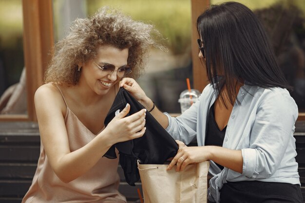 Tre donne eleganti con borse della spesa in una città