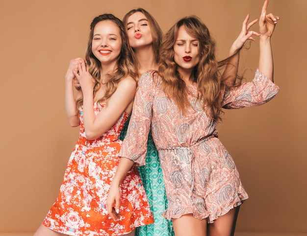 Tre giovani belle ragazze sorridenti in abiti casual estivi alla moda e in occhiali da sole. Posa sexy spensierata delle donne.