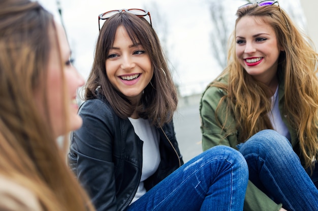 Tre giovani donne che parlano e ridono in strada.