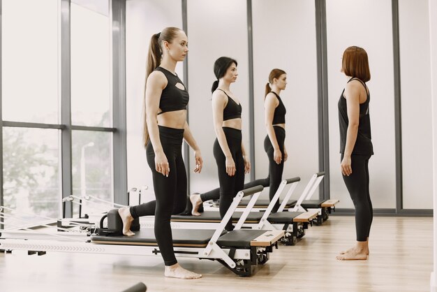 Tre giovani donne in forma che si allenano in palestra. Donne che indossano abiti sportivi neri. Ragazze caucasiche che si esercitano con l'attrezzatura.