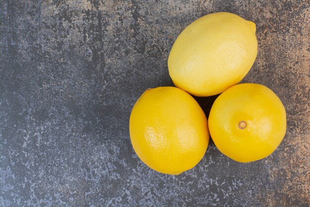 Tre limoni freschi interi su uno spazio di marmo