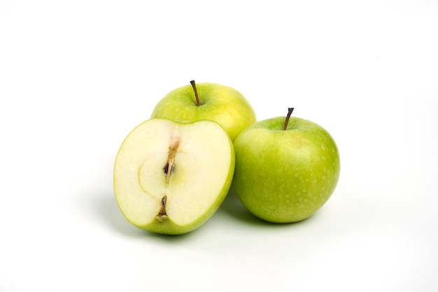 Tre mele fresche intere e affettate su sfondo bianco.