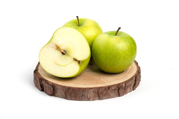 Tre mele fresche intere ed affettate sul pezzo di legno.