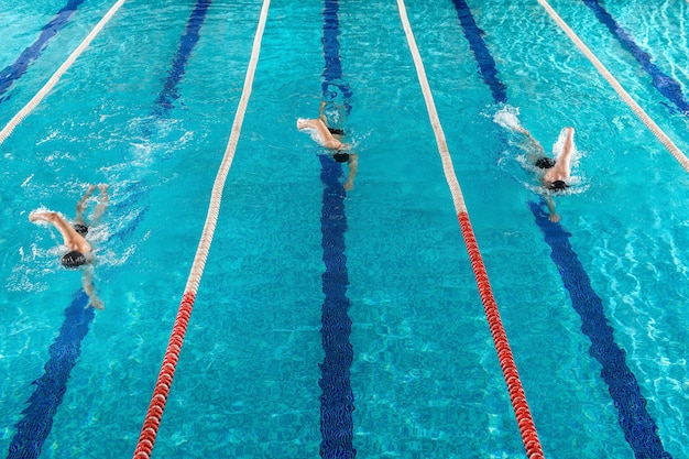 Tre nuotatori maschi che corrono uno contro l'altro