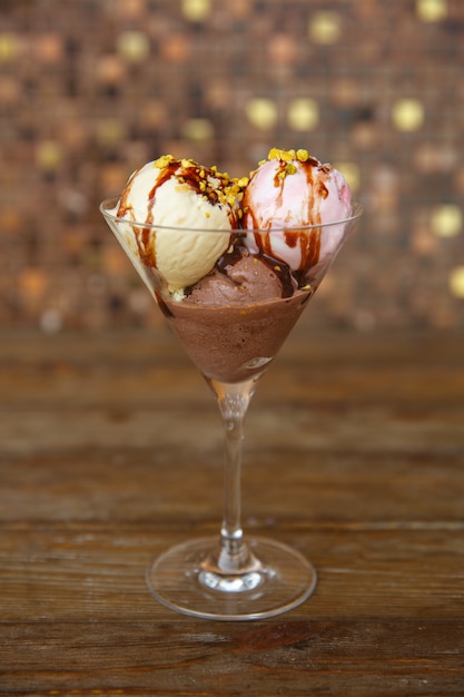 Tre palline di gelato con fragola, vaniglia e caffè ricoperti di sciroppo di cioccolato