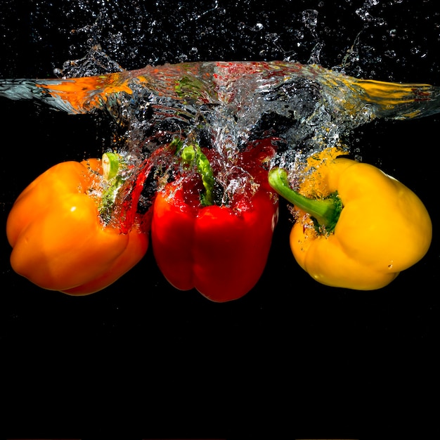 Tre peperoni che cadono nell&#39;acqua della spruzzata