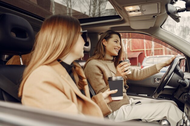 Tre ragazze sedute dentro la macchina e bevendo un caffè