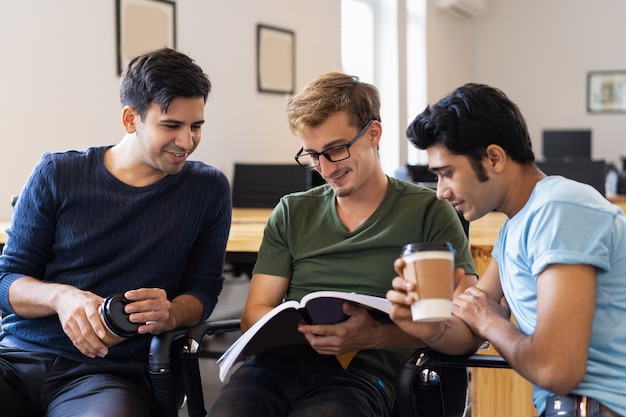 Tre studenti che leggono insieme il libro di testo e bevono