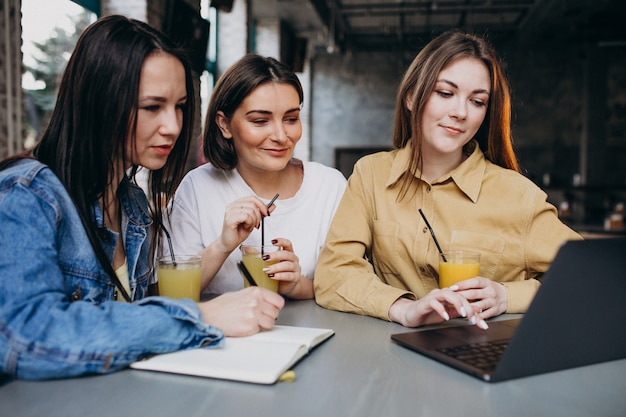 Tre studenti che si preparano per l'esame con il computer portatile in un caffè