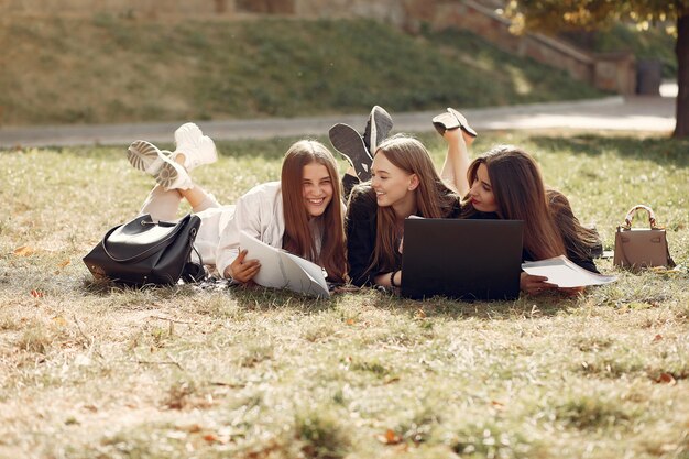 Tre studenti seduti su un prato con il portatile