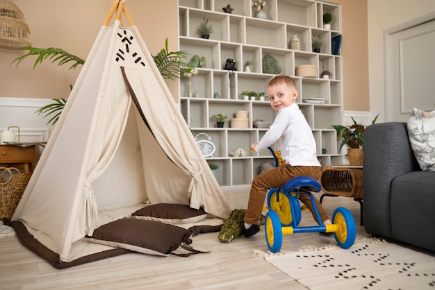 Triciclo di guida del bambino felice del colpo pieno all'interno