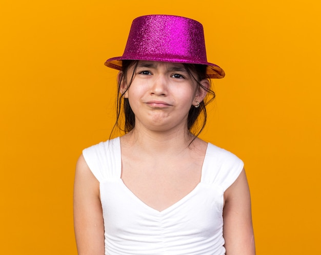 triste giovane ragazza caucasica con cappello viola partito isolato sulla parete arancione con spazio di copia