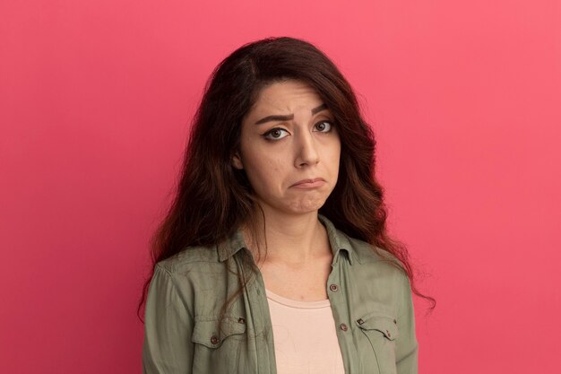 Triste guardando la telecamera giovane bella ragazza che indossa la maglietta verde oliva isolata sulla parete rosa