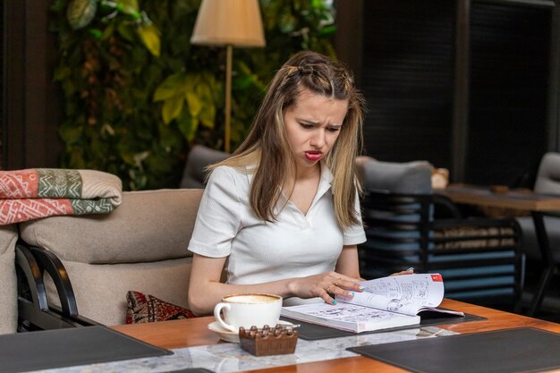 Triste ragazza seduta al ristorante e guardando il suo libro