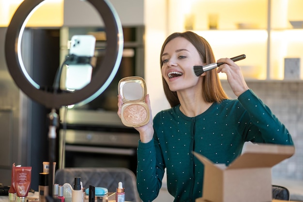 Trucco. Donna che tiene la spazzola per il viso e fa il trucco