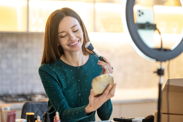 Trucco. Donna che tiene la spazzola per il viso e fa il trucco