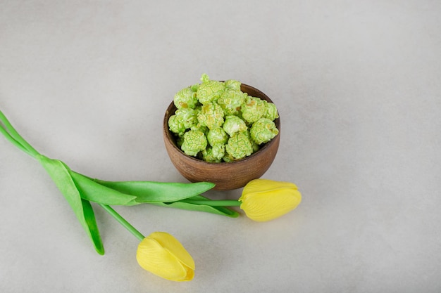 Tulipani gialli e una ciotola di caramelle popcorn sul tavolo di marmo.