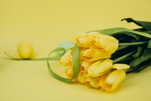 Tulipani gialli e uova di Pasqua su sfondo giallo