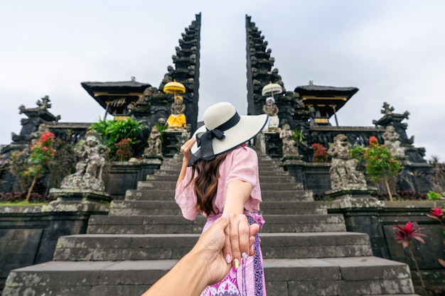 Turista che tiene la mano dell'uomo e lo conduce al tempio di Besakih a Bali, Indonesia