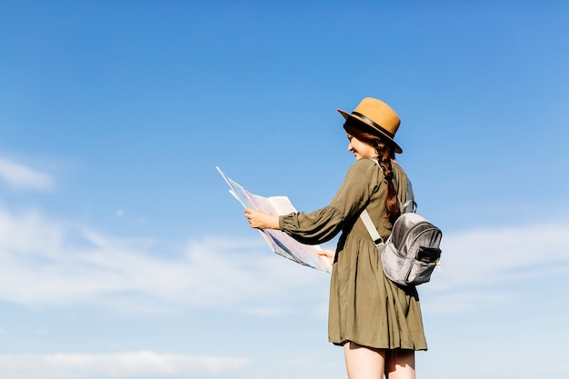 Turista con mappa sullo sfondo del cielo soleggiato