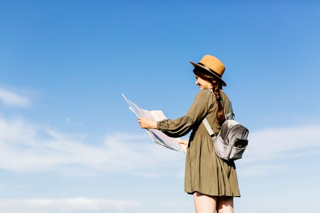 Turista con mappa sullo sfondo del cielo soleggiato