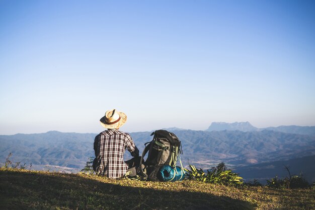 Turista dalla cima della montagna. i raggi del sole. l&#39;uomo indossa un grande zaino contro la luce del sole