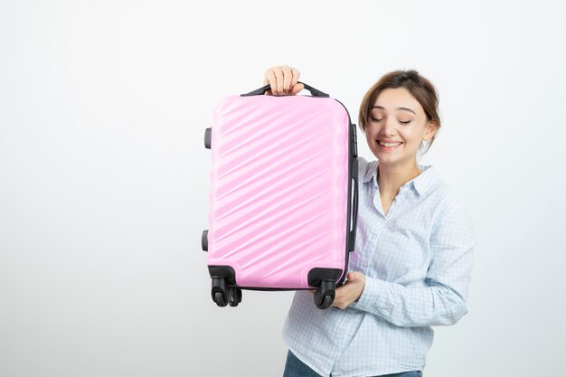 Turista della donna che sta e che tiene la valigia rosa di viaggio. Foto di alta qualità