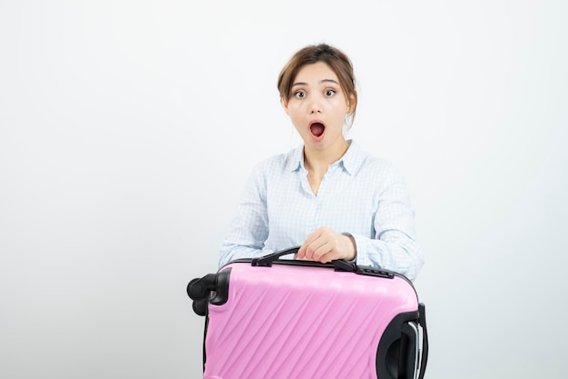 Turista della donna che sta e che tiene la valigia rosa di viaggio. Foto di alta qualità