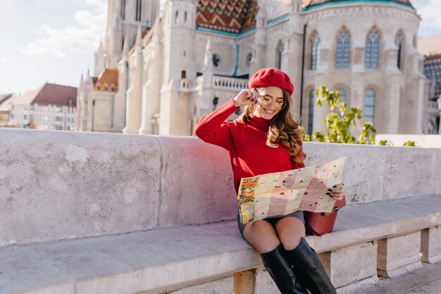 Turista femminile abbastanza francese che esplora la vecchia città europea con la mappa