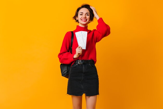 Turista femminile beato in maglione rosso che tiene i biglietti