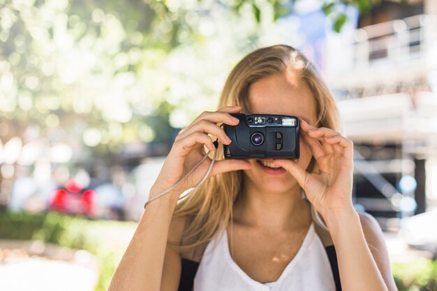 Turista femminile cliccando le foto attraverso la fotocamera digitale all&#39;aperto