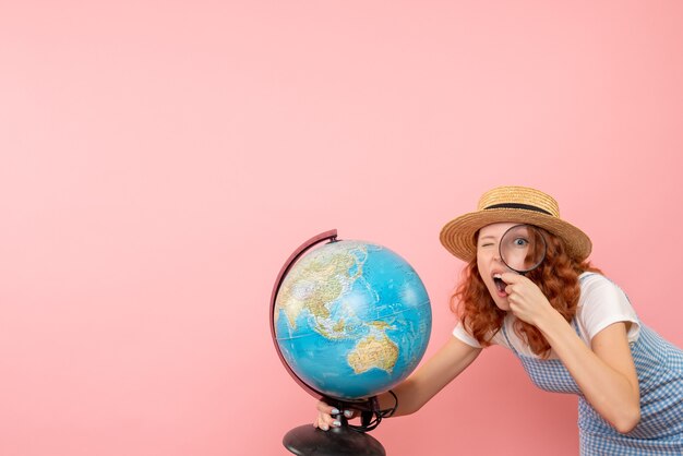 Turista femminile di vista frontale che esplora globo con lente d'ingrandimento