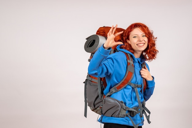 Turista femminile di vista frontale che va in viaggio di montagna con lo zaino