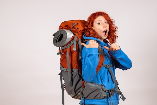 Turista femminile di vista frontale che va in viaggio di montagna con lo zaino