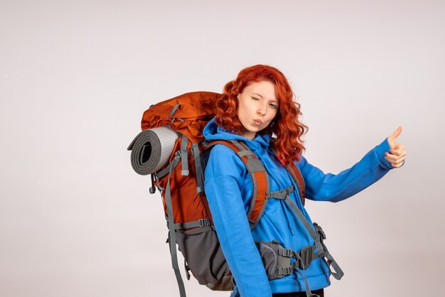 Turista femminile di vista frontale che va in viaggio di montagna con lo zaino