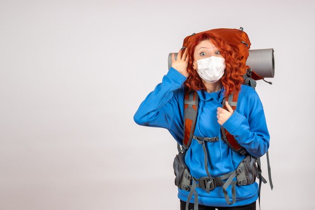 Turista femminile di vista frontale che va in viaggio in montagna in maschera con lo zaino