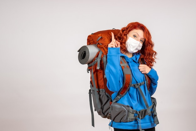 Turista femminile di vista frontale che va in viaggio in montagna in maschera con lo zaino